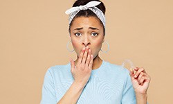 worried woman holding an Invisalign tray