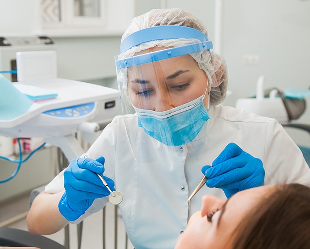 Dental team member wearing dual face masks to treat dental patient