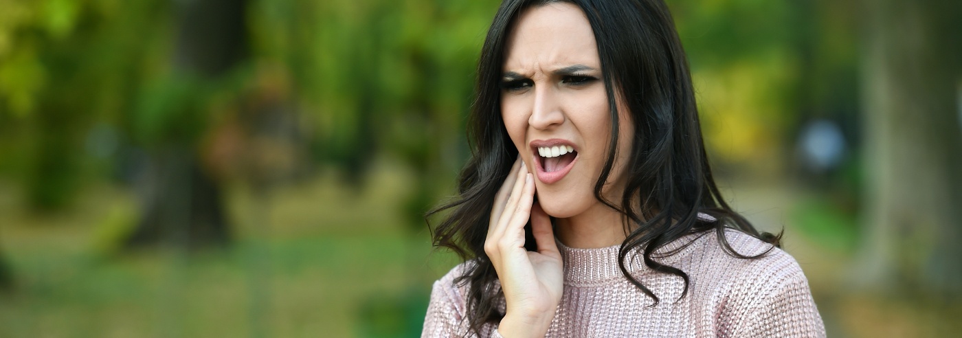Woman in need of emergency dentistry holding cheek in pain