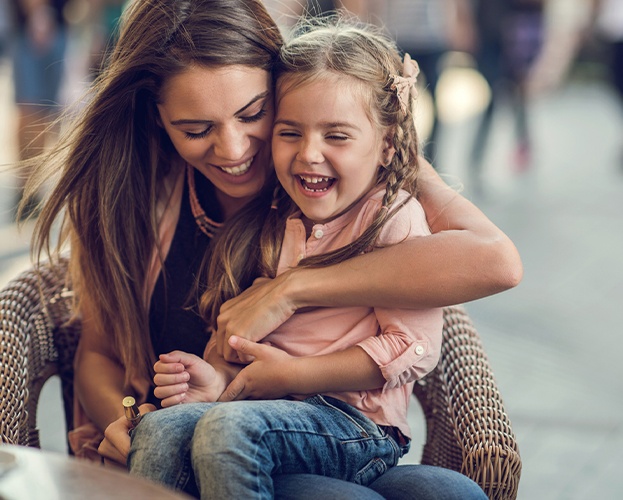 Mother hugging laughing daughter after pulp therapy