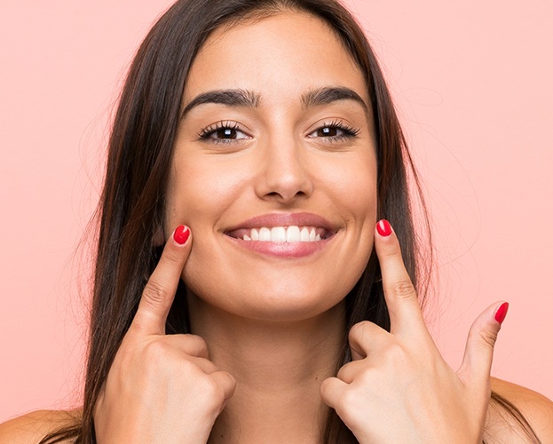 Woman pointing to smile after teeth whitening treatment