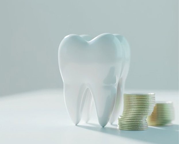 Model of a tooth next to a stack of coins