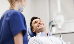 Man leaning back in dental chair and grinning at his dentist
