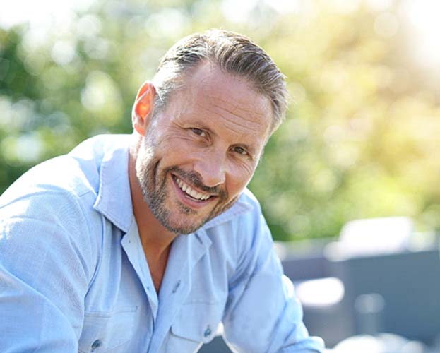 man smiling after answering his questions about implant dentures in West Seneca