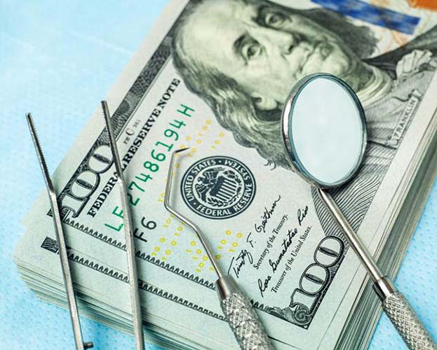 Money and dental tools representing the cost of dental emergencies in West Seneca