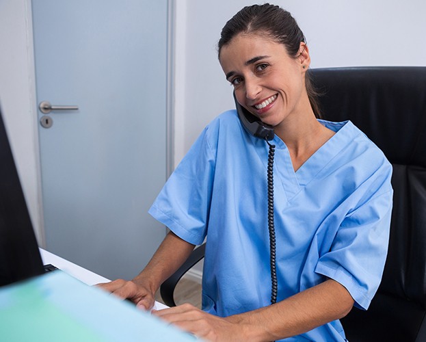 Dental team member smiling while answering the phone