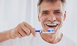 man brushing his teeth to keep up oral hygiene