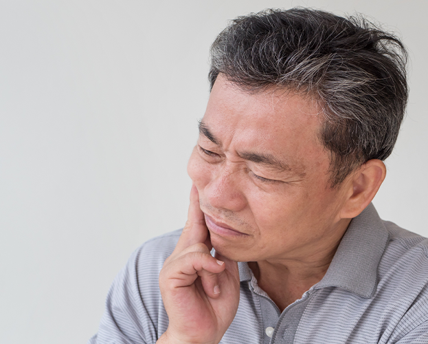 Man wincing and holding the side of his jaw in pain