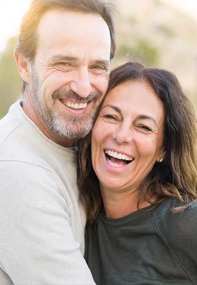 Laughing man and woman holding each other outdoors