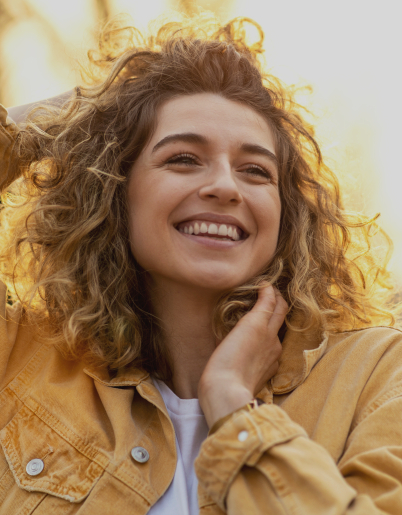 Woman with curly hair smiling outdoors