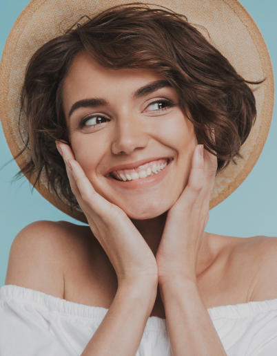 Woman in sunhat grinning and holding her face