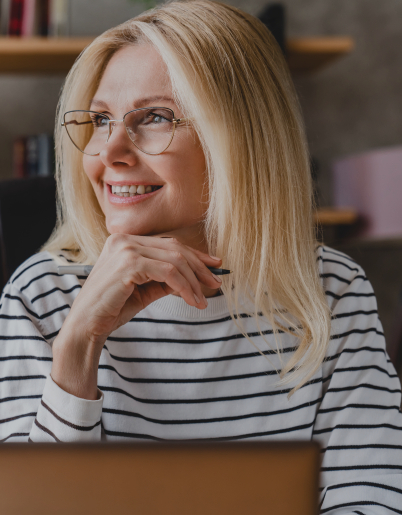 Woman in striped shirt sitting at desk and holding pen