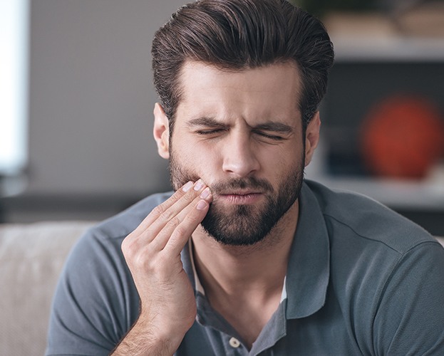 Man in need of root canal therapy holding jaw