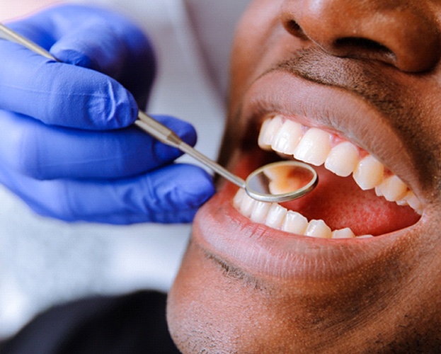 man having his gums inspected by dentist