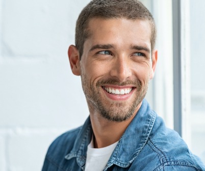 Man in blue shirt smiling and looking off to the side