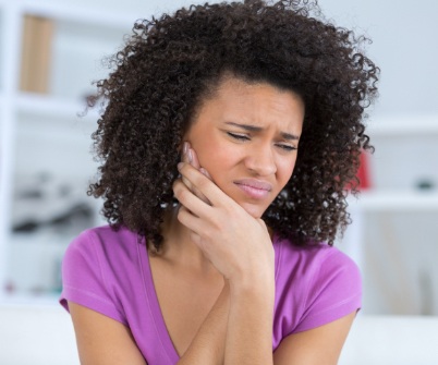 Woman in need of emergency dentistry holding jaw