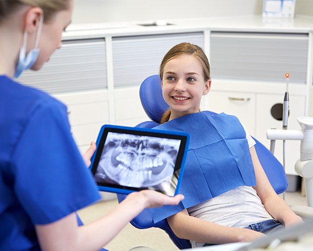 Dentist looking at young patient's digital x-rays on tablet computer