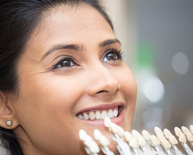 Woman smiling while dentist holds a shade chart for veneers in West Seneca