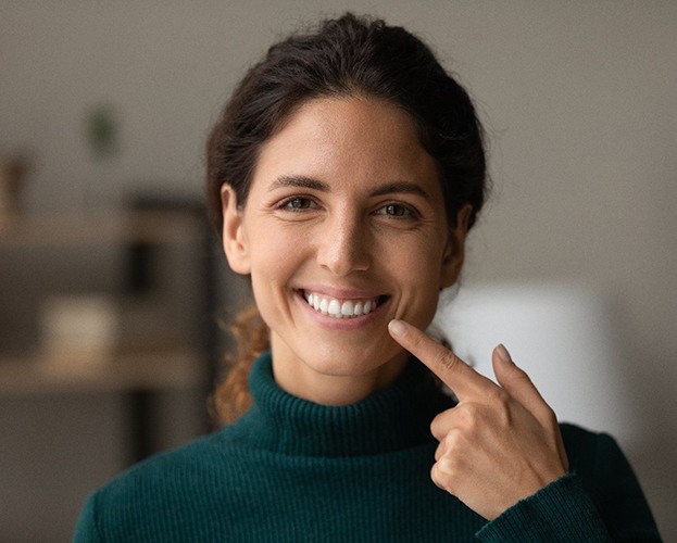 smiling woman pointing at her whitening teeth