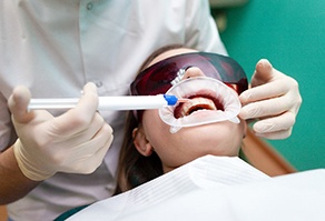 dentist applying whitening gel onto a patient’s teeth