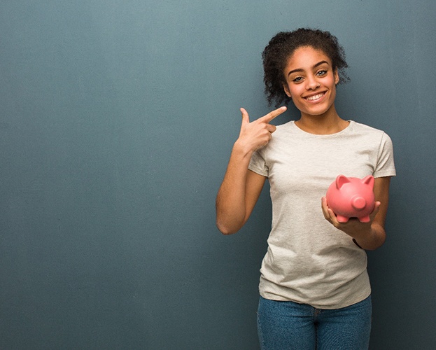 woman holding a piggy bank and pointing to her smile
