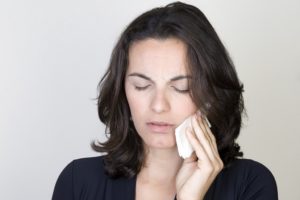 woman in pain holding compress to face