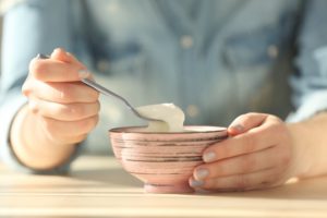 hands holding a spoon and bowl of yogurt