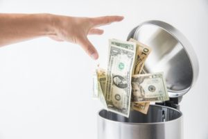 person throwing money into the waste basket