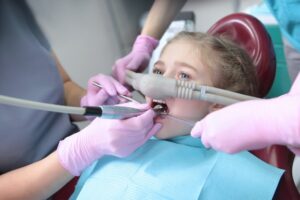 young girl having dental work done with a nitrous oxide nasal mask on
