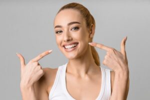 woman with a wide smile pointing her fingers to her mouth