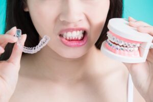 woman with worried mouth holding Invisalign and braces model
