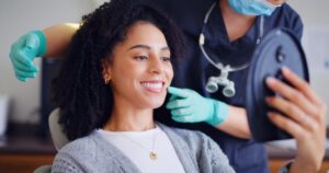 woman looking at her new smile in the mirror with the dentist