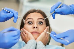 woman in fear with gloved hands with dental instruments around her