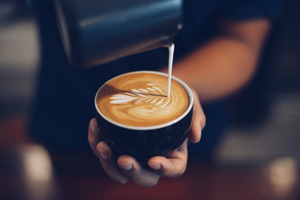 Pouring cream into a cup of coffee