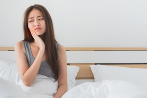 Woman sitting up in bed with a toothache